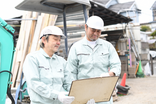 工事現場で進行表の確認をする二人の作業員