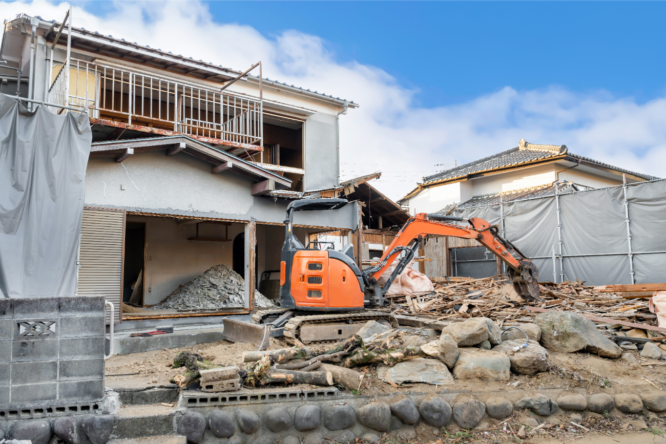 重機とそれに解体される木造家屋